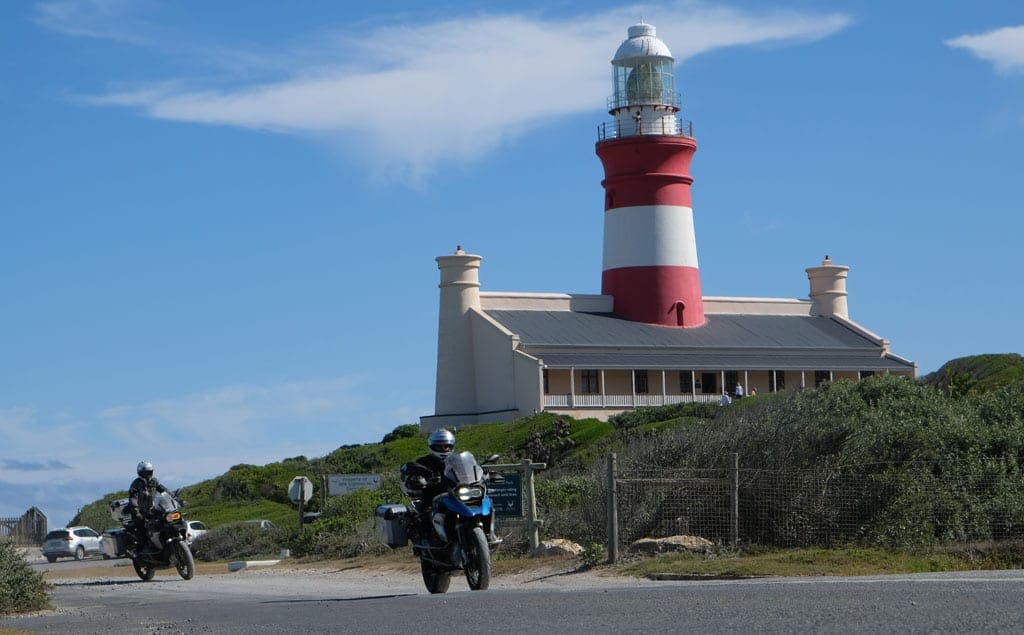 Tip of Africa 2 Two of the bikers ride past a lighthouse.