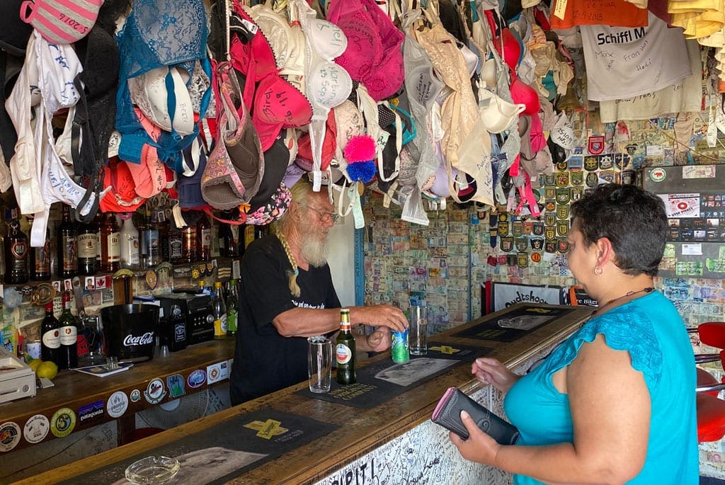 Into the little Karoo 5 A lady purchasing drinks at a bar with bras hanging from the ceiling.