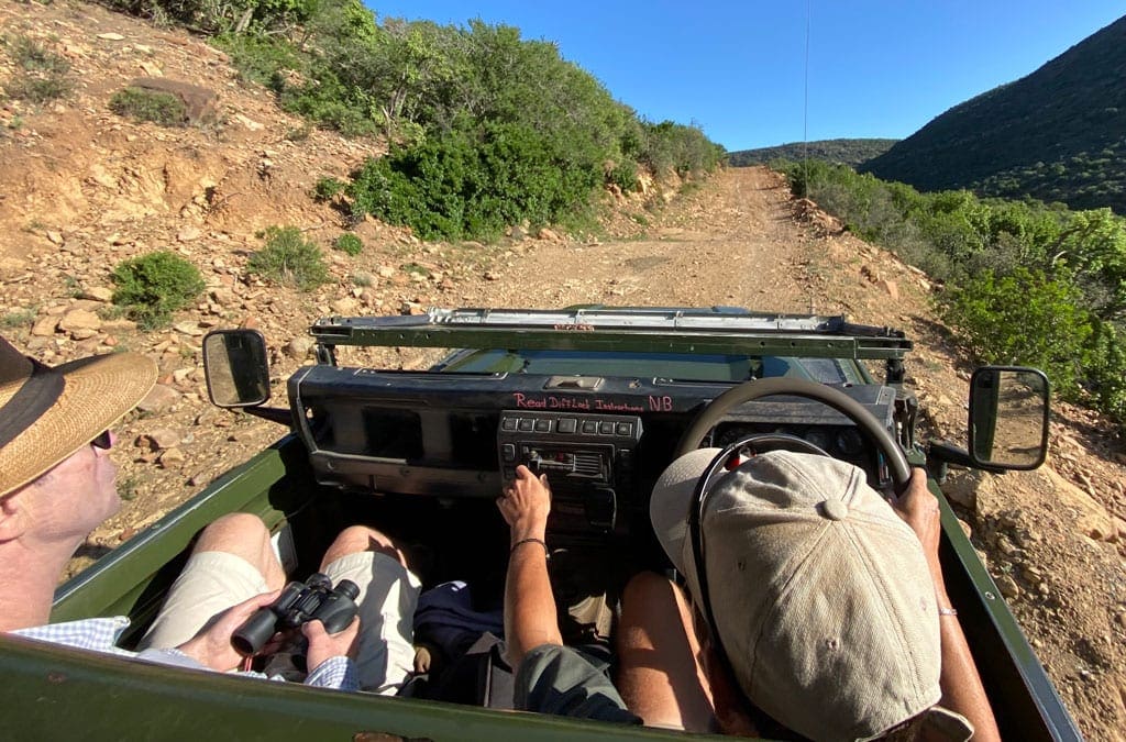 The group drive a small jeep along a small dirt road.