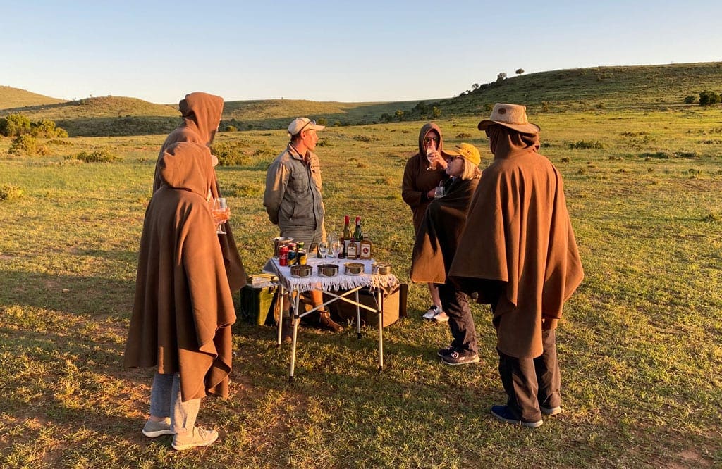 The group take a food and drink break in the middle of a field as the sun sets.