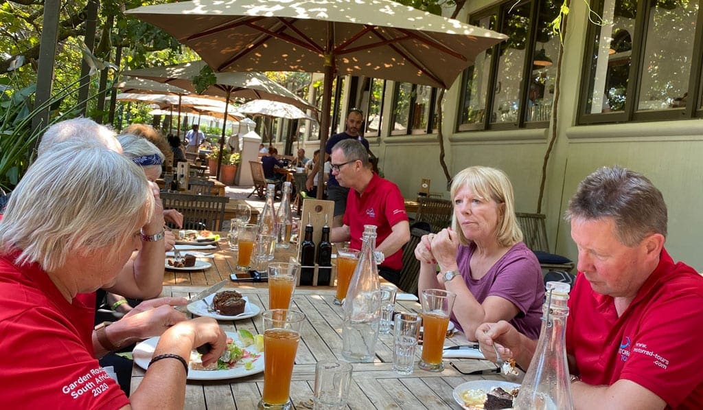 The group have lunch at a restaurant outdoors. 